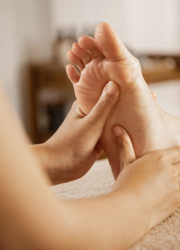 Masseuse massaging female foot at the spa.